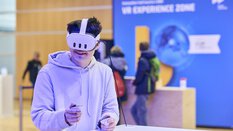 Mann testet eine Virtual-Reality-Anwendung mit Headset und Controllern in der VR Experience Zone auf der bauma 2025.
