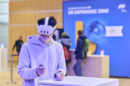 Mann testet eine Virtual-Reality-Anwendung mit Headset und Controllern in der VR Experience Zone auf der bauma 2025.