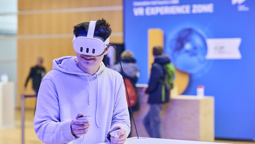 Mann testet eine Virtual-Reality-Anwendung mit Headset und Controllern in der VR Experience Zone auf der bauma 2025.