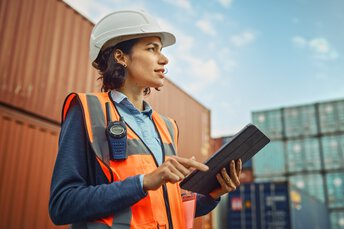 Frau koordiniert Gütertransport mit Funkgerät und Touchpad