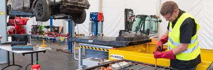 Battery packs for electric vehicles in a workshop, machines and equipment in the background.