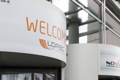 Sign with WELCOME and the LOPEC logo above a revolving door at the entrance.
