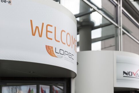 Schild mit WELCOME und dem LOPEC-Logo über einer Drehtür am Eingang.