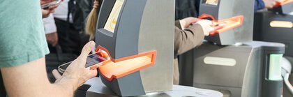 Person mit World of Quantum Ticket auf dem Smartphone am Drehkreuz im Messeeingang
