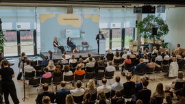 Carsten Schneider spricht am Rednerpult auf dem SZ-Nachhaltigkeitsgipfel vor einem sitzenden Publikum; auf der Bühne sitzen zwei weitere Personen vor einer hellblauen Veranstaltungswand der Süddeutschen Zeitung. 