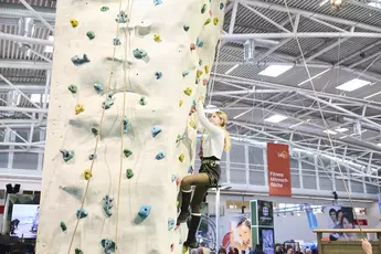 Visitor climbing the climbing tower at f.re.e 2025, showcasing her climbing skills